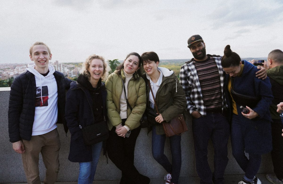 A group of friends posing in a city setting, wearing warm jackets and enjoying their trip
