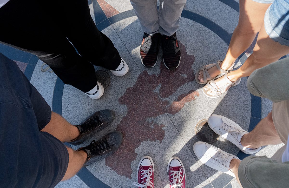 A group standing on a famous landmark, with feet on a marked circle on the ground