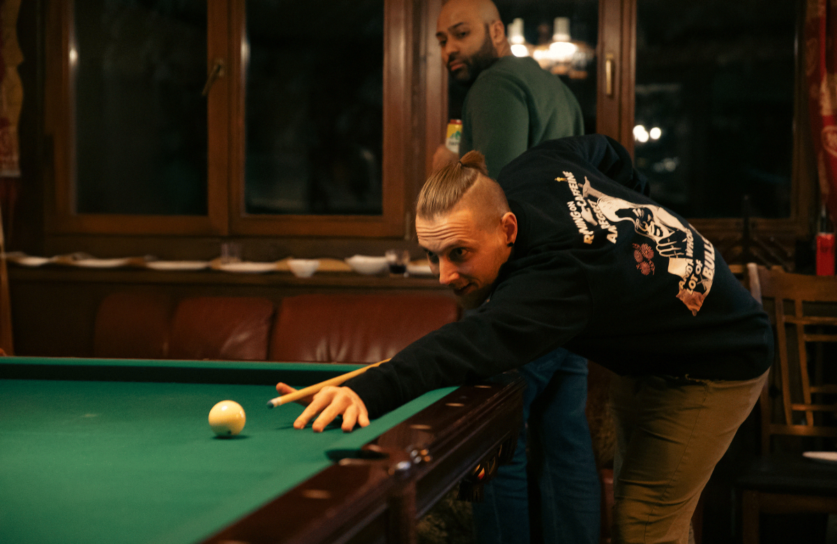 A person playing pool in a rustic lodge setting, focused on making a perfect shot