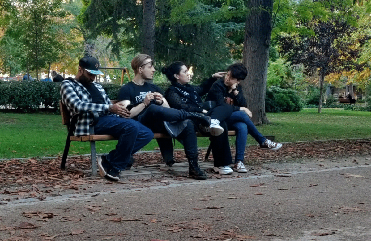A group of people sitting on a park bench, enjoying a quiet moment together in an autumn setting