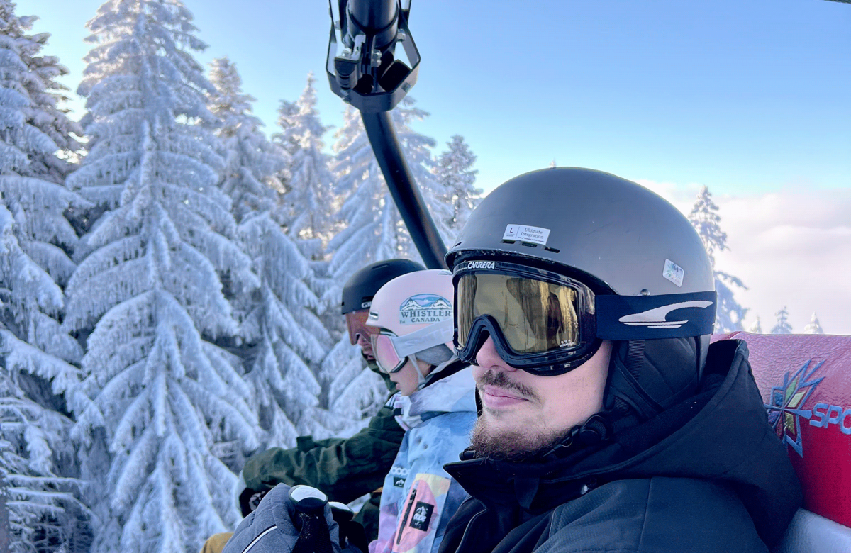 A group of friends wearing ski helmets and goggles, admiring the snowy trees on a mountain
